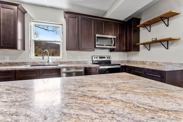 kitchen featuring dark brown cabinets, open shelves, a sink, stainless steel appliances, and light stone countertops