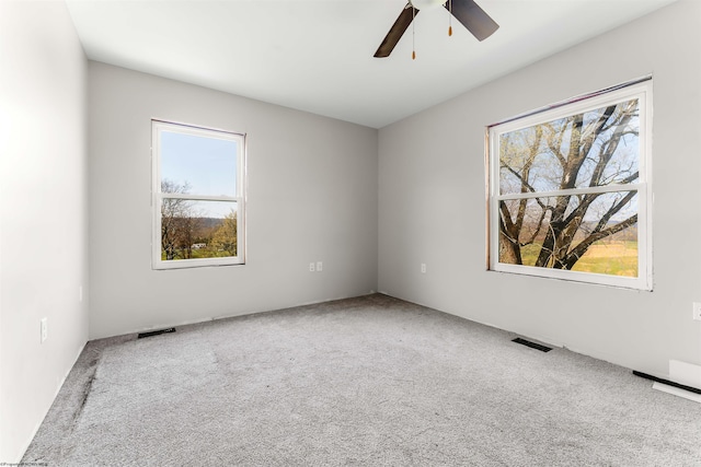 carpeted spare room featuring visible vents and ceiling fan