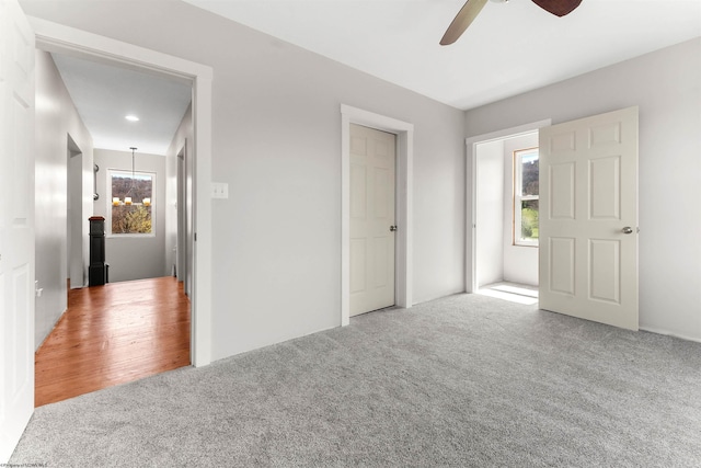 unfurnished bedroom featuring ceiling fan with notable chandelier and carpet