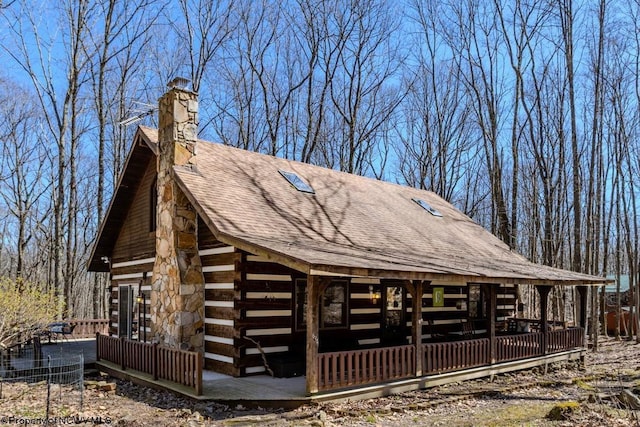 exterior space with a shingled roof, a chimney, and log exterior