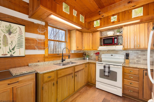kitchen with a sink, electric range, light wood-style floors, backsplash, and under cabinet range hood