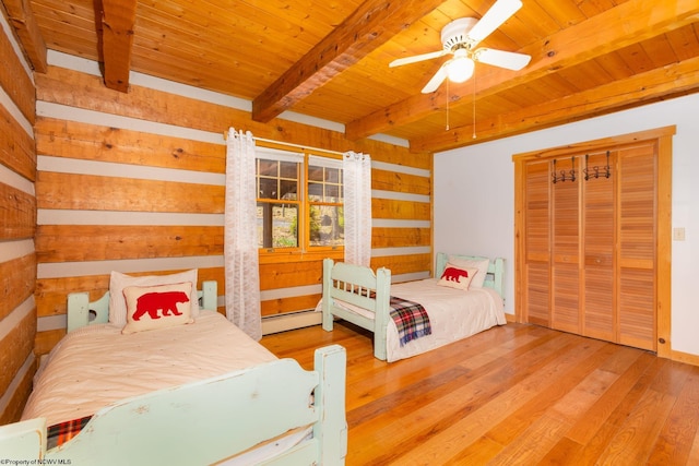 bedroom featuring baseboard heating, wood finished floors, wooden walls, wood ceiling, and beam ceiling