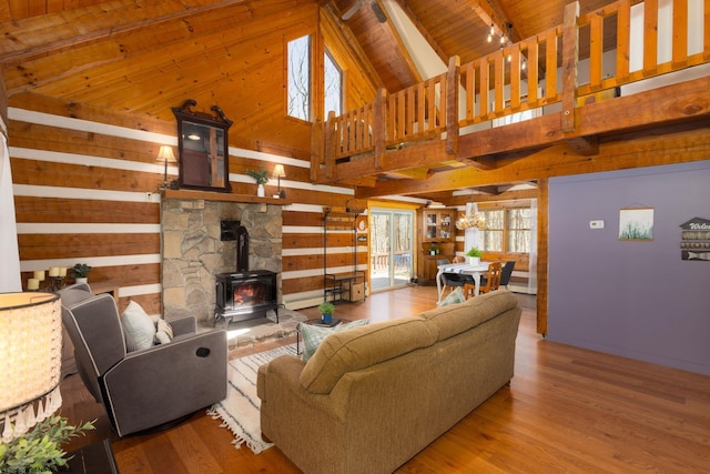 living room with wood walls, wood finished floors, a wood stove, wooden ceiling, and beamed ceiling