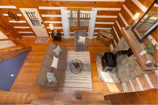 living area with wooden walls, wood finished floors, and a wood stove