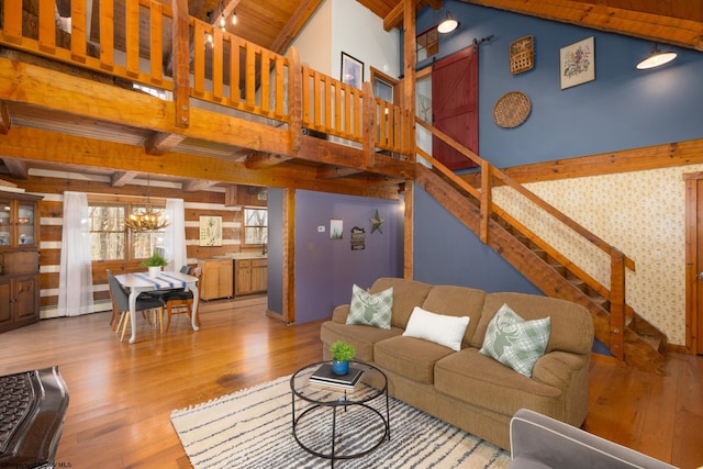 living area with a chandelier, wood finished floors, stairs, and beamed ceiling