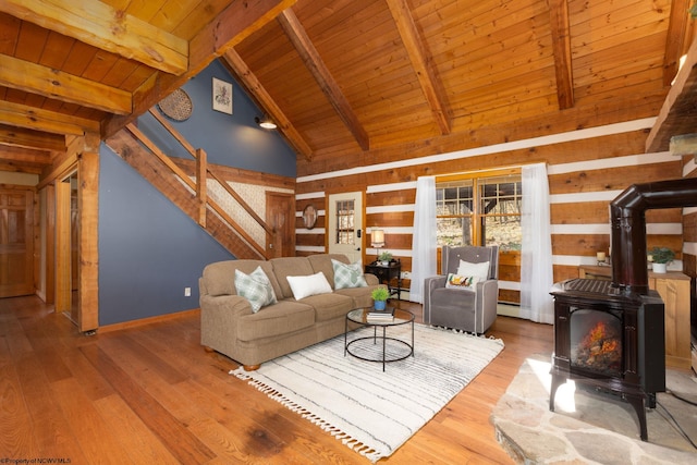 living room featuring hardwood / wood-style floors, wood walls, a wood stove, beam ceiling, and wood ceiling