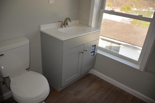 half bath with wood finished floors, vanity, and toilet