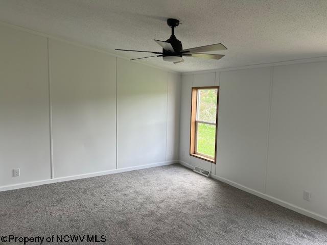 unfurnished room featuring a textured ceiling, carpet, visible vents, and ceiling fan