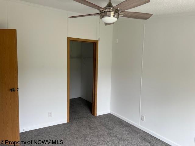 unfurnished bedroom with a spacious closet, a ceiling fan, carpet floors, a closet, and baseboards