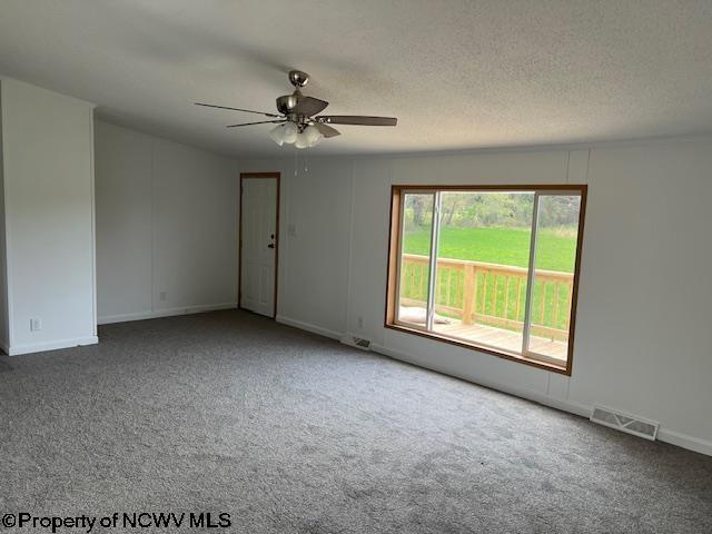 carpeted spare room featuring baseboards, a ceiling fan, and visible vents