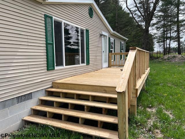 wooden terrace featuring a yard and stairs