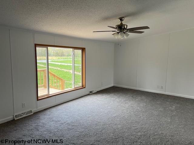 carpeted empty room featuring a ceiling fan, a textured ceiling, and visible vents