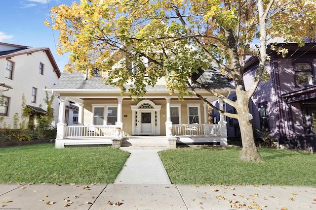 bungalow-style house with a porch, a front lawn, and roof with shingles