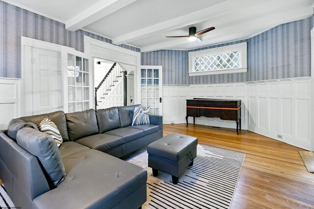 living area with wallpapered walls, wood finished floors, beam ceiling, and a decorative wall