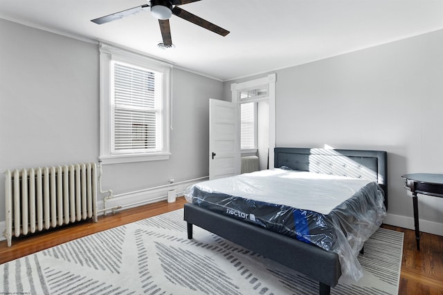 bedroom featuring radiator, wood finished floors, baseboards, and ornamental molding