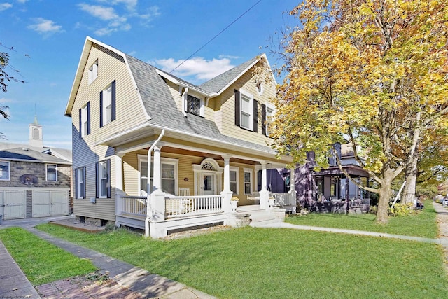 view of front facade featuring a gambrel roof, a shingled roof, covered porch, a front yard, and a garage