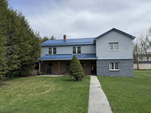 traditional-style home with stone siding, a front lawn, a chimney, and metal roof