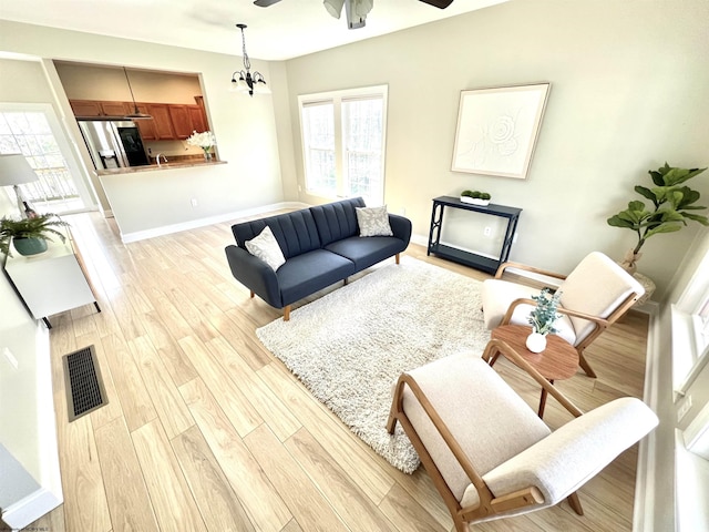 1029 Olivia Way, Morgantown, WV 26508 - living area featuring light wood-type flooring, visible vents, baseboards, and ceiling fan with notable chandelier