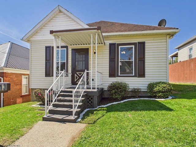 bungalow-style home with a front lawn, fence, and roof with shingles