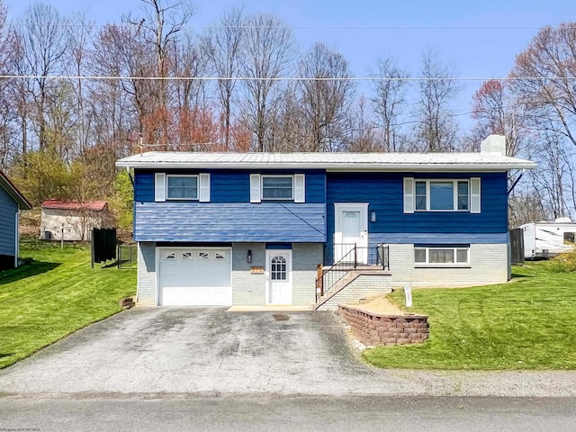 split foyer home featuring a front lawn, brick siding, aphalt driveway, and metal roof