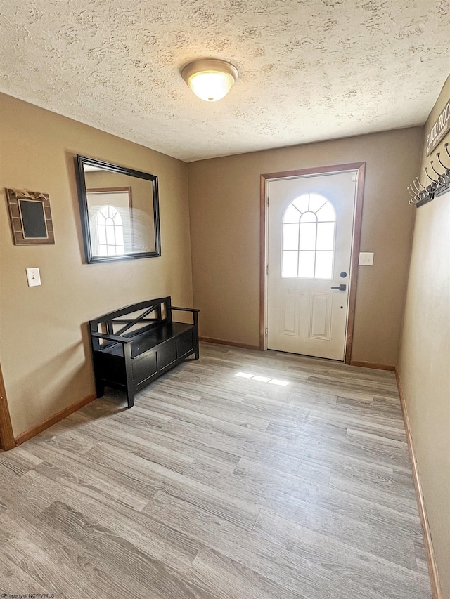 entrance foyer featuring baseboards, light wood-style floors, and a textured ceiling