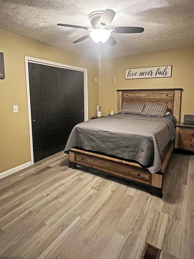 bedroom featuring wood finished floors, a textured ceiling, and a ceiling fan