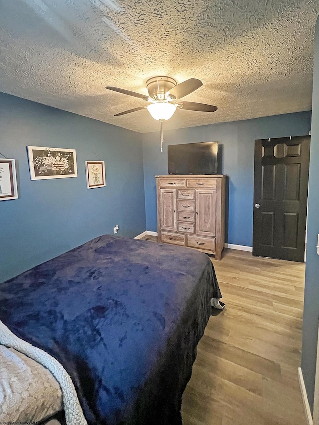 bedroom featuring baseboards, a textured ceiling, and light wood-style flooring