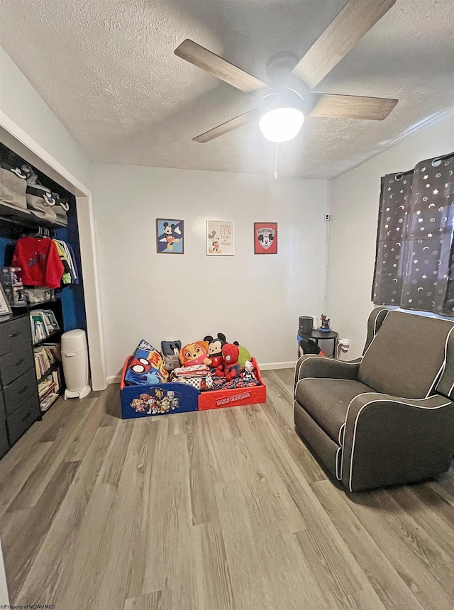 bedroom featuring wood finished floors, a textured ceiling, baseboards, and ceiling fan