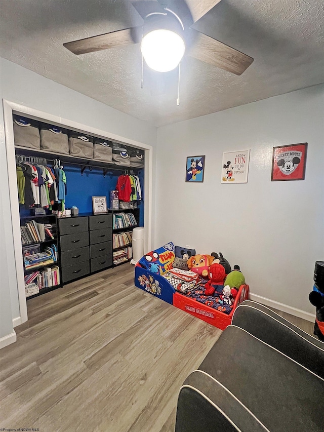bedroom with wood finished floors, a textured ceiling, and ceiling fan