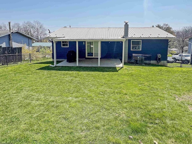 back of house featuring a yard, a patio area, a chimney, and fence
