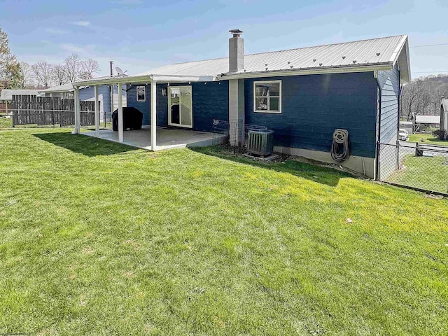 back of house featuring fence, a patio area, a yard, and metal roof