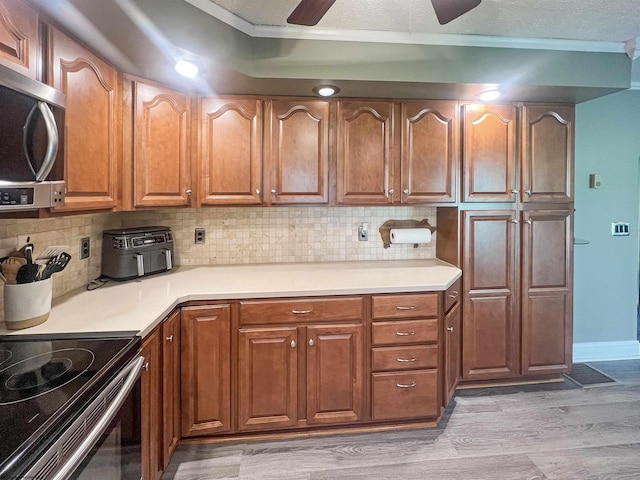 kitchen with stainless steel appliances, light countertops, light wood-style floors, decorative backsplash, and ceiling fan