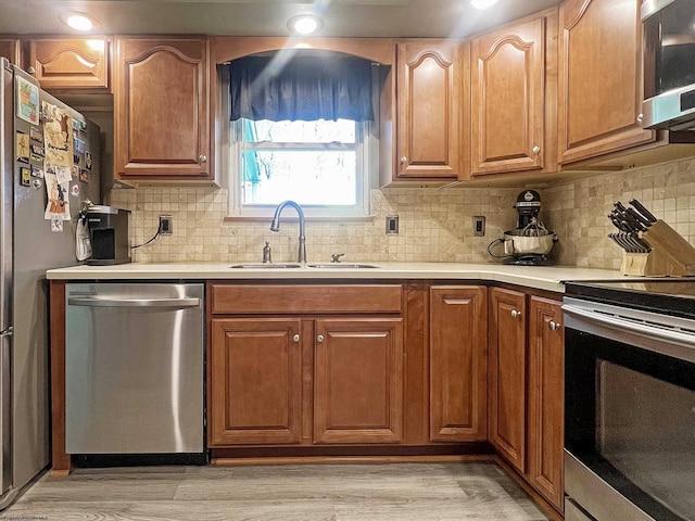 kitchen with stainless steel appliances, light countertops, a sink, and backsplash