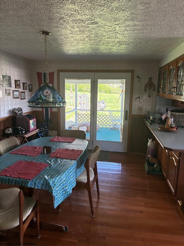 dining room featuring wallpapered walls, wood finished floors, and a textured ceiling