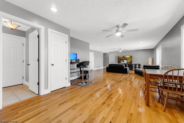 dining space featuring recessed lighting, a ceiling fan, light wood-style floors, baseboards, and a textured ceiling