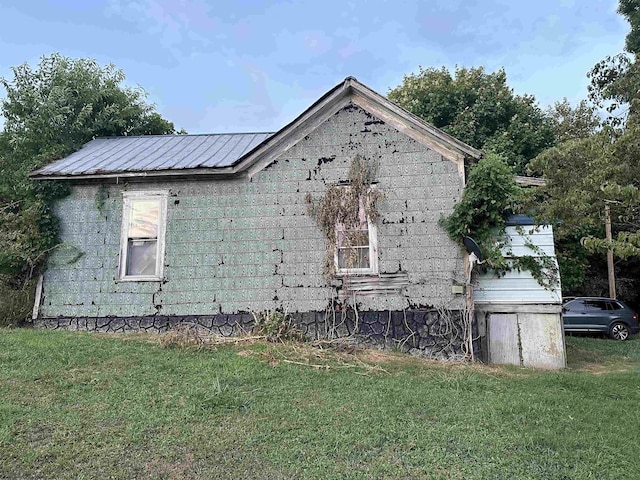 view of side of home featuring metal roof and a lawn