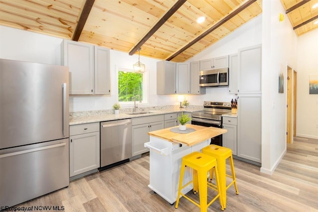 kitchen with wood ceiling, a sink, appliances with stainless steel finishes, light wood-style floors, and beam ceiling