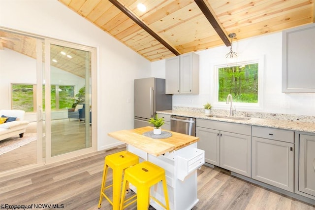 kitchen with wooden ceiling, stainless steel appliances, vaulted ceiling with beams, and a sink