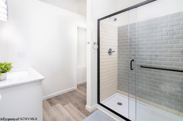 full bath with a stall shower, wood finished floors, and baseboards
