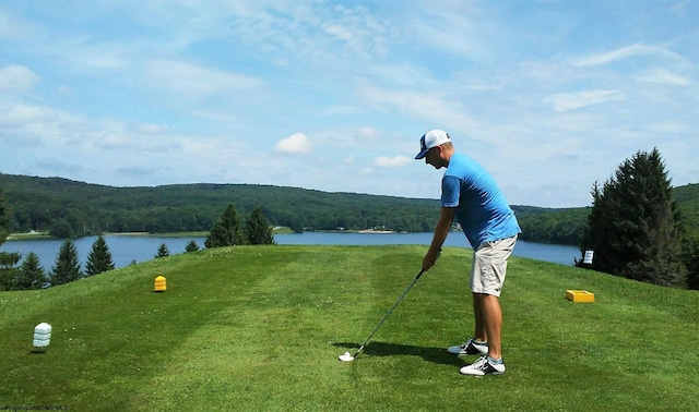 view of community with a lawn, a water view, and a forest view