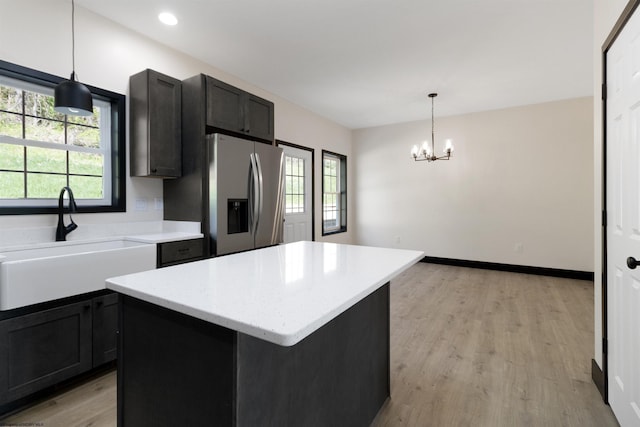 kitchen featuring a sink, a chandelier, a center island, light wood-type flooring, and stainless steel fridge