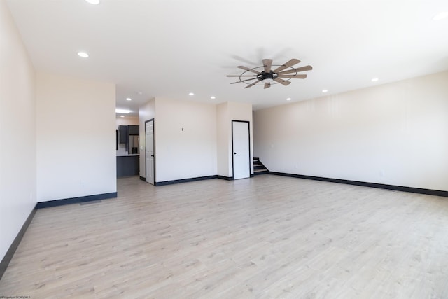 empty room featuring baseboards, recessed lighting, light wood-type flooring, and stairway