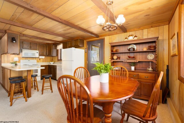 dining room featuring beam ceiling, wooden ceiling, wood walls, and light colored carpet