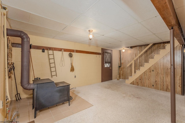 finished basement with concrete block wall, wood walls, stairway, and a drop ceiling