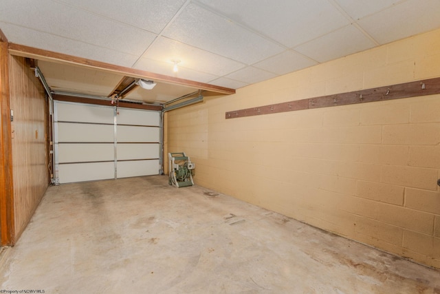garage with a garage door opener and concrete block wall