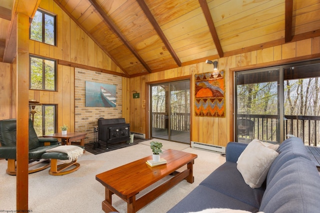carpeted living room featuring wooden walls, plenty of natural light, a wood stove, and baseboard heating