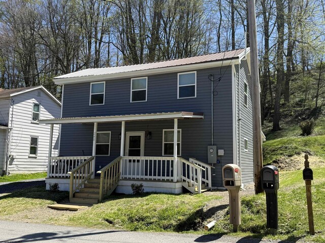 view of front facade featuring a porch, a front lawn, and metal roof