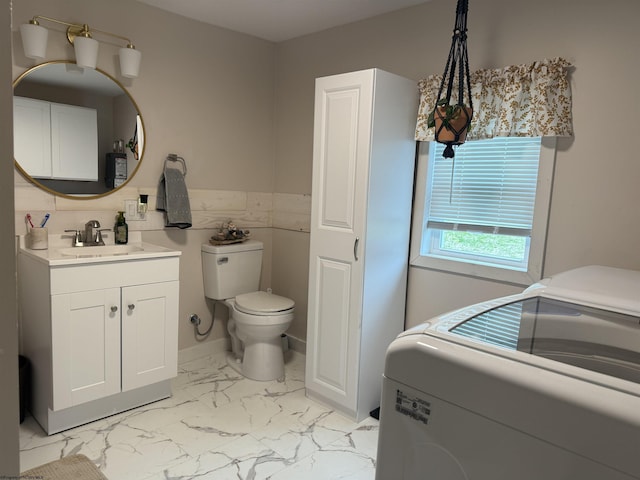 bathroom featuring toilet, vanity, marble finish floor, and washer / dryer