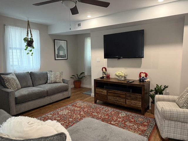 living area featuring baseboards, visible vents, wood finished floors, and ceiling fan