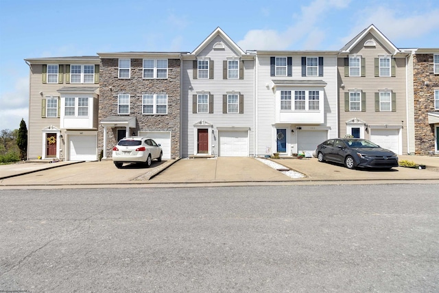 view of property with driveway, stone siding, and a garage
